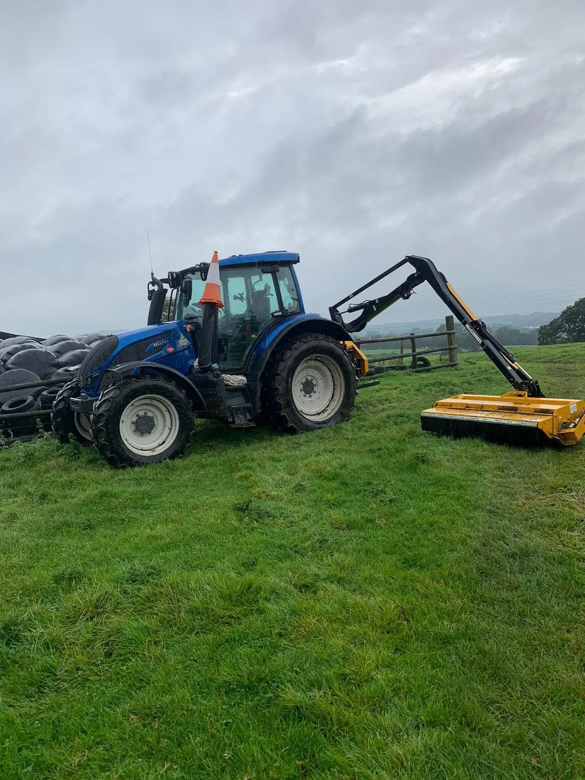 Tractor with a hedge cutter working along a field hedge