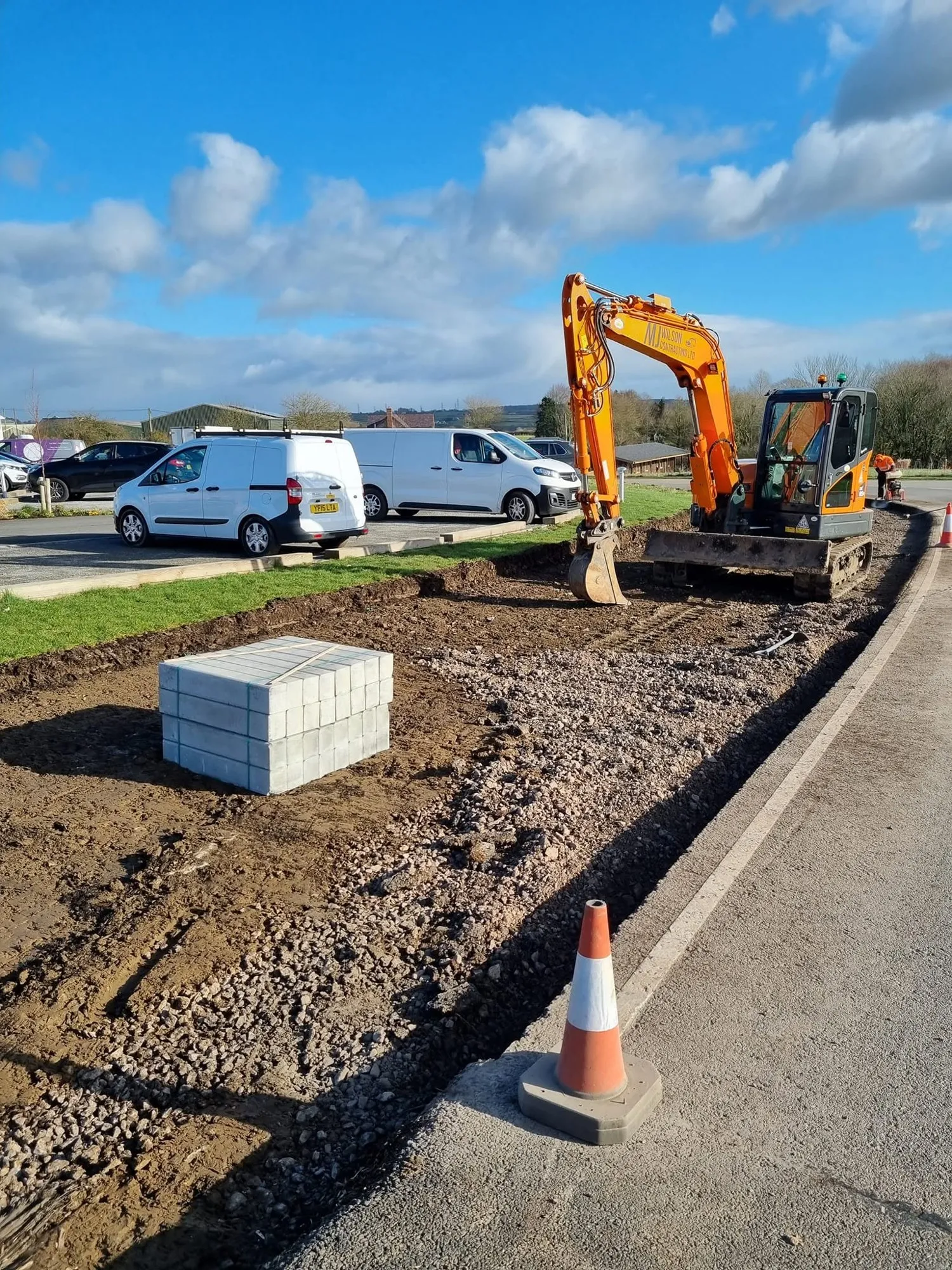 Excavator and kerb blocks beside a newly laid kerb line