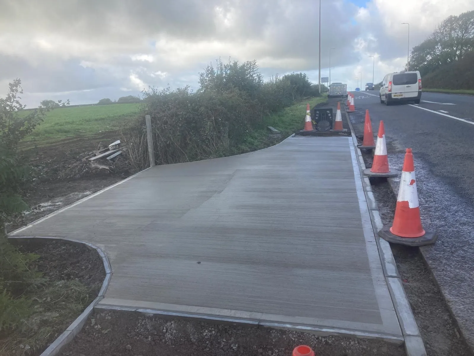 New concrete access road with kerbs beside a public road