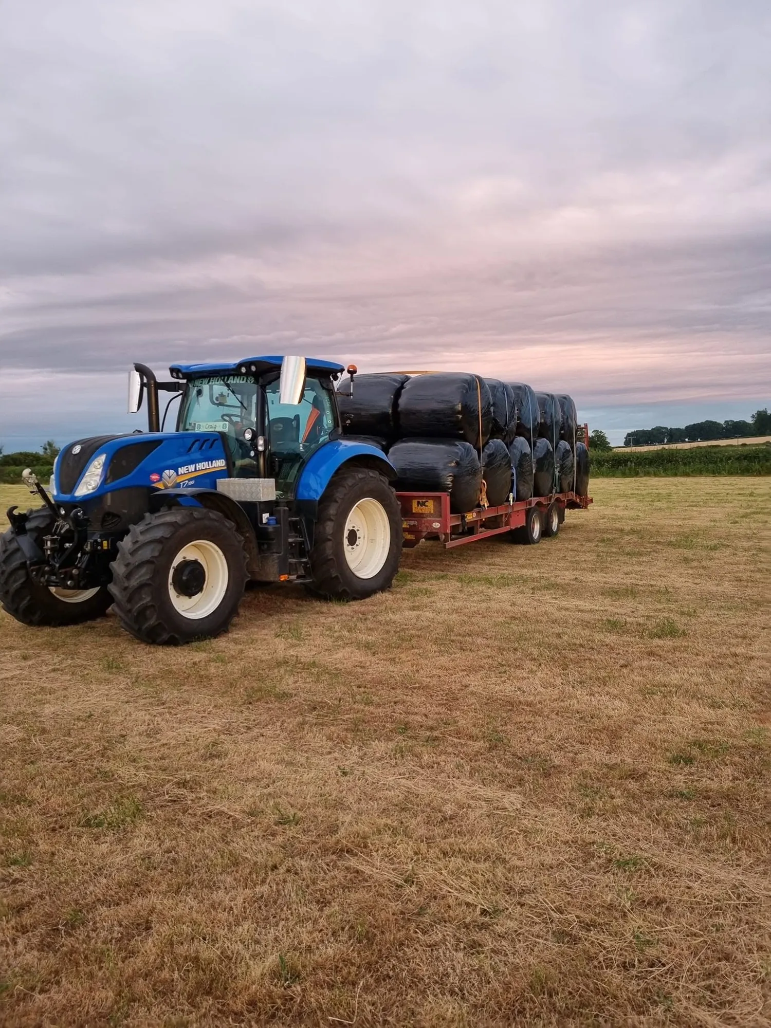Tractor and trailer loaded with wrapped round bales