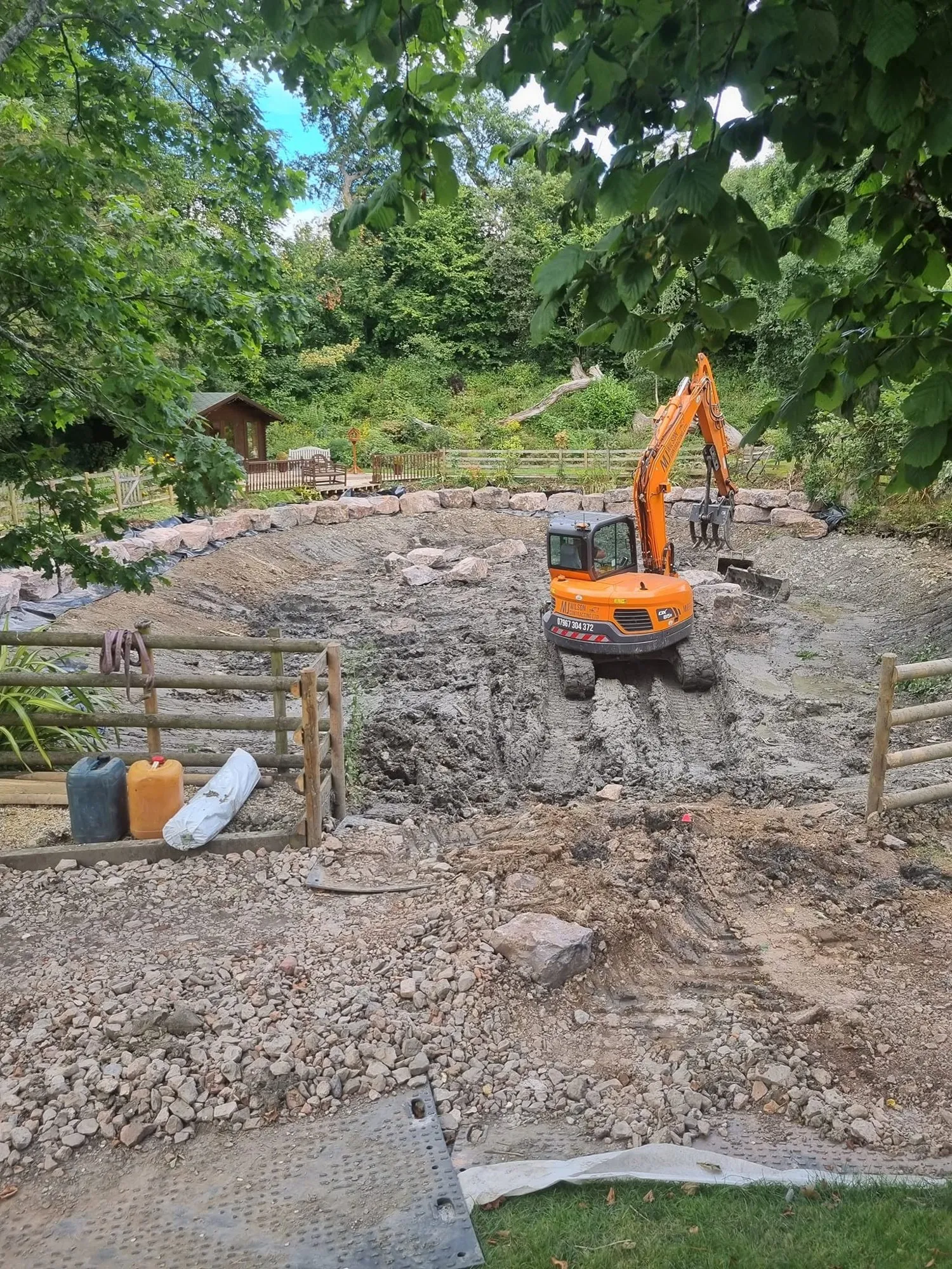 Excavator clearing silt from the bed of the drained pond