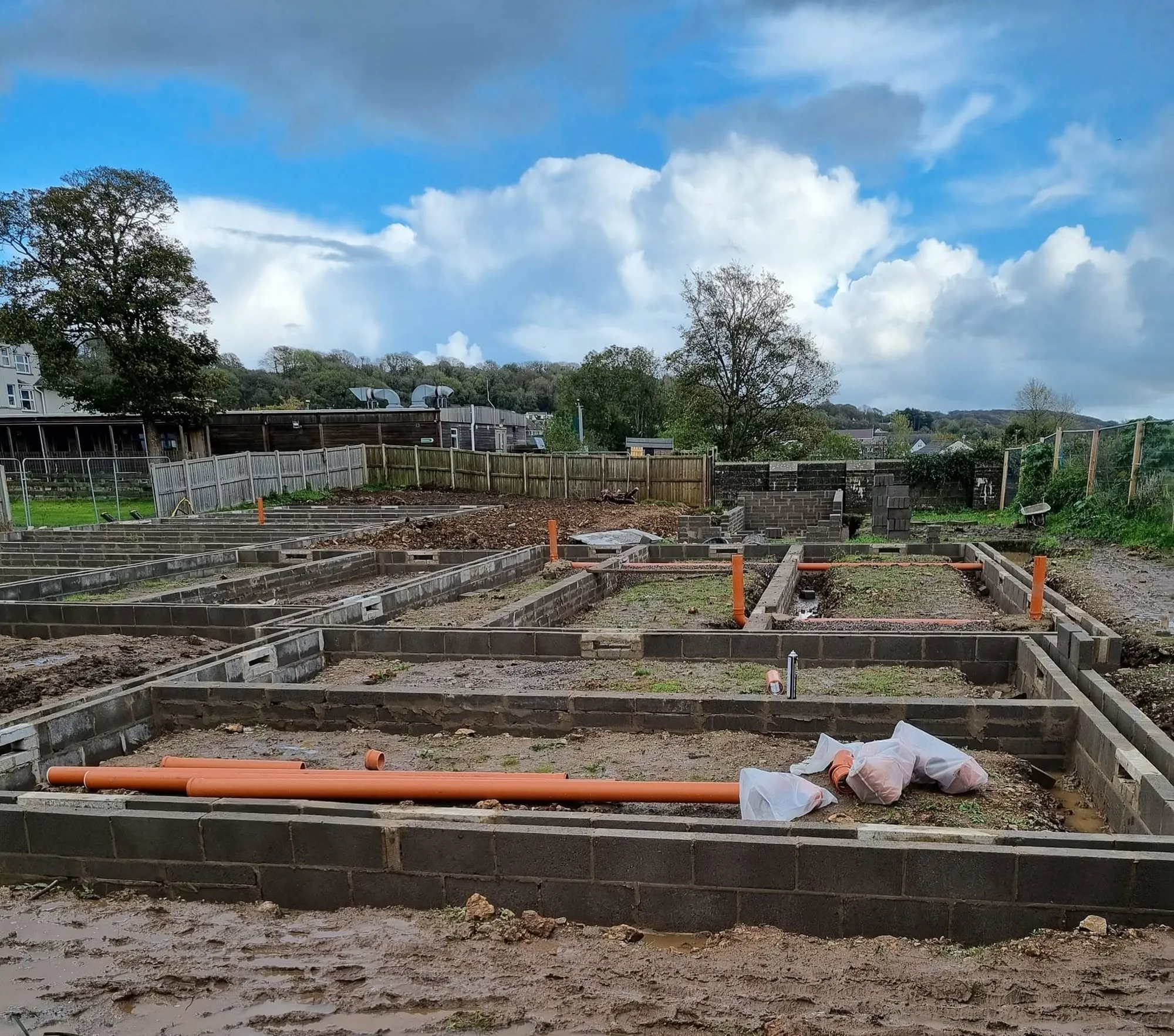 Rows of blockwork footings with drainage pipe laid out across the site