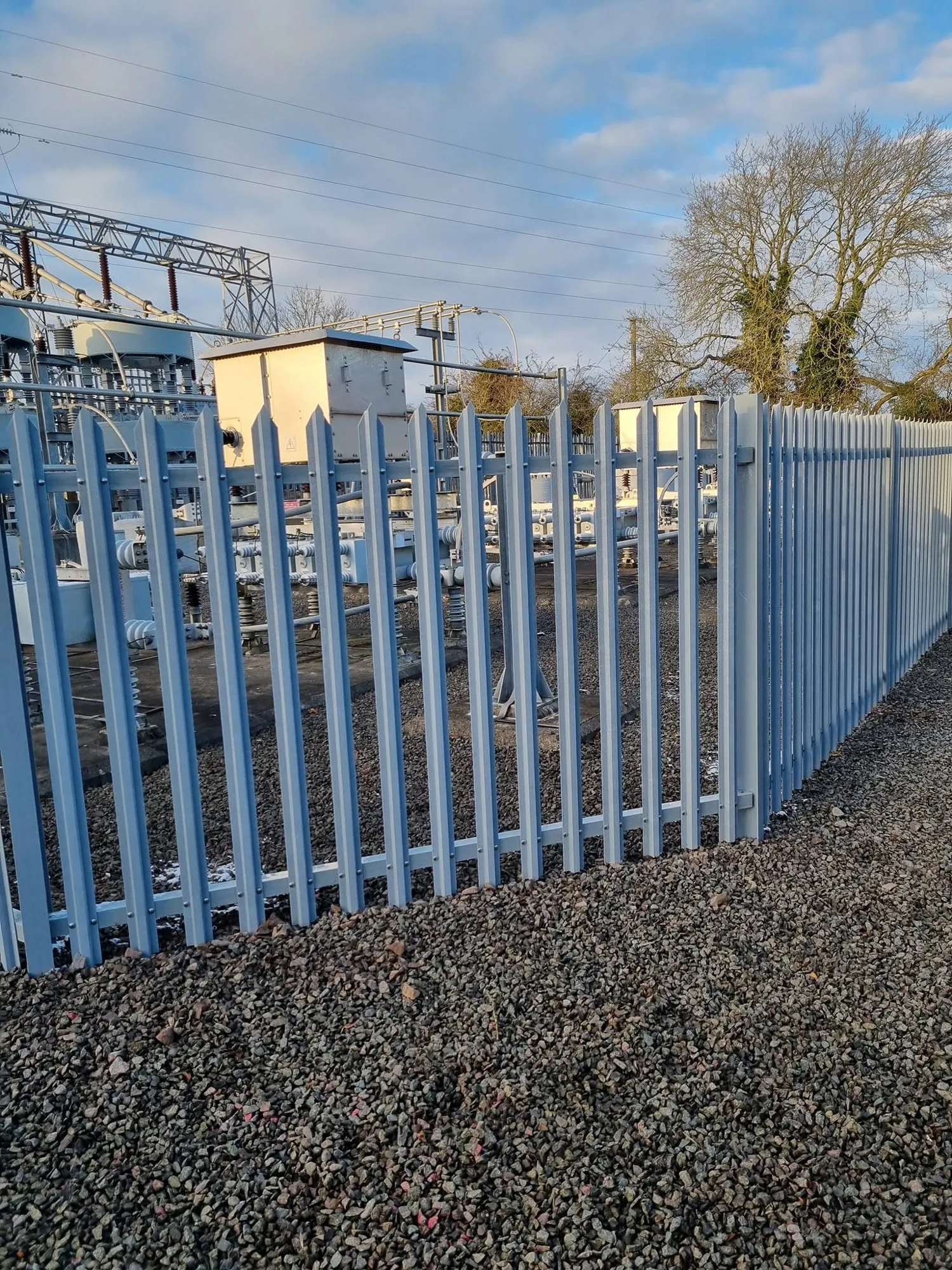 Close view of a palisade fence line on a gravel surface