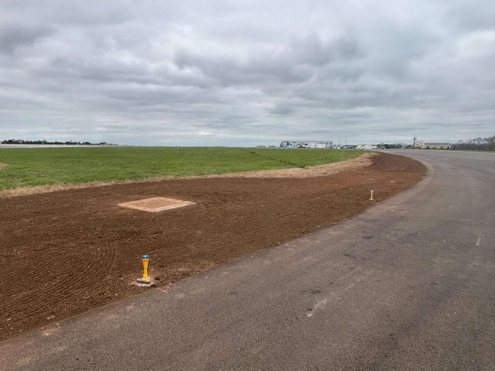 Cultivated and levelled verge beside a taxiway, ready for seeding
