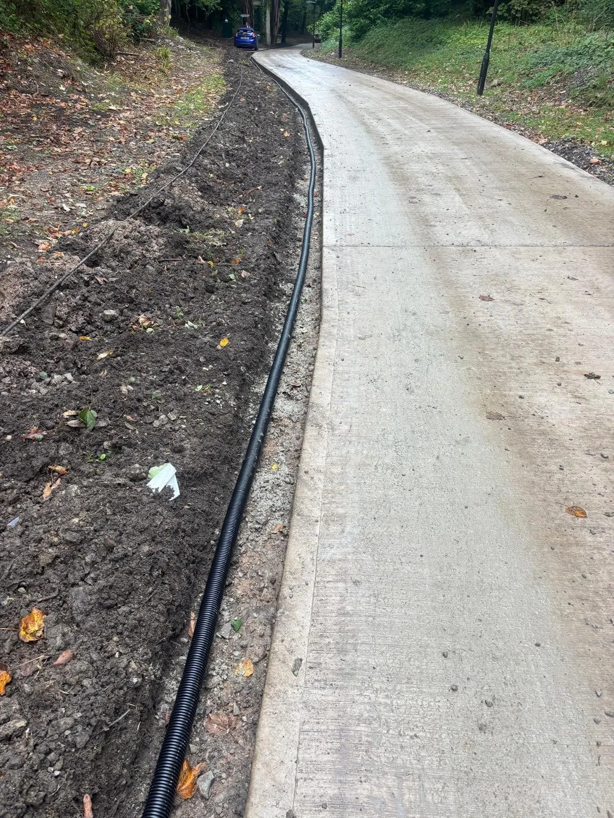 New concrete access road with ducting laid alongside through woodland