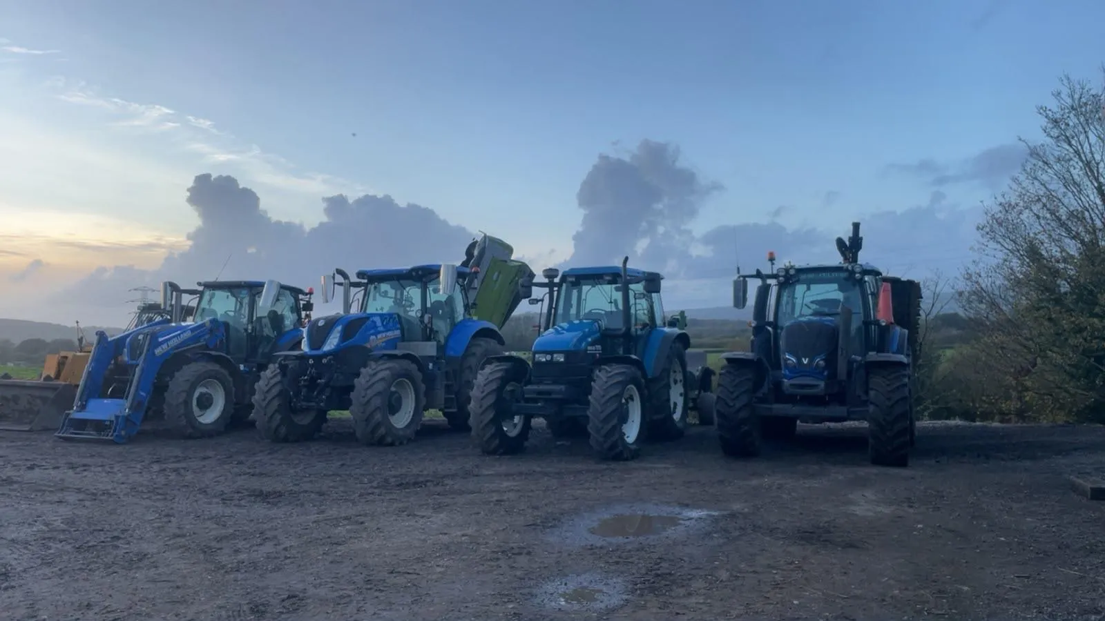 Four of our tractors lined up on the yard at dusk, New Holland and Valtra