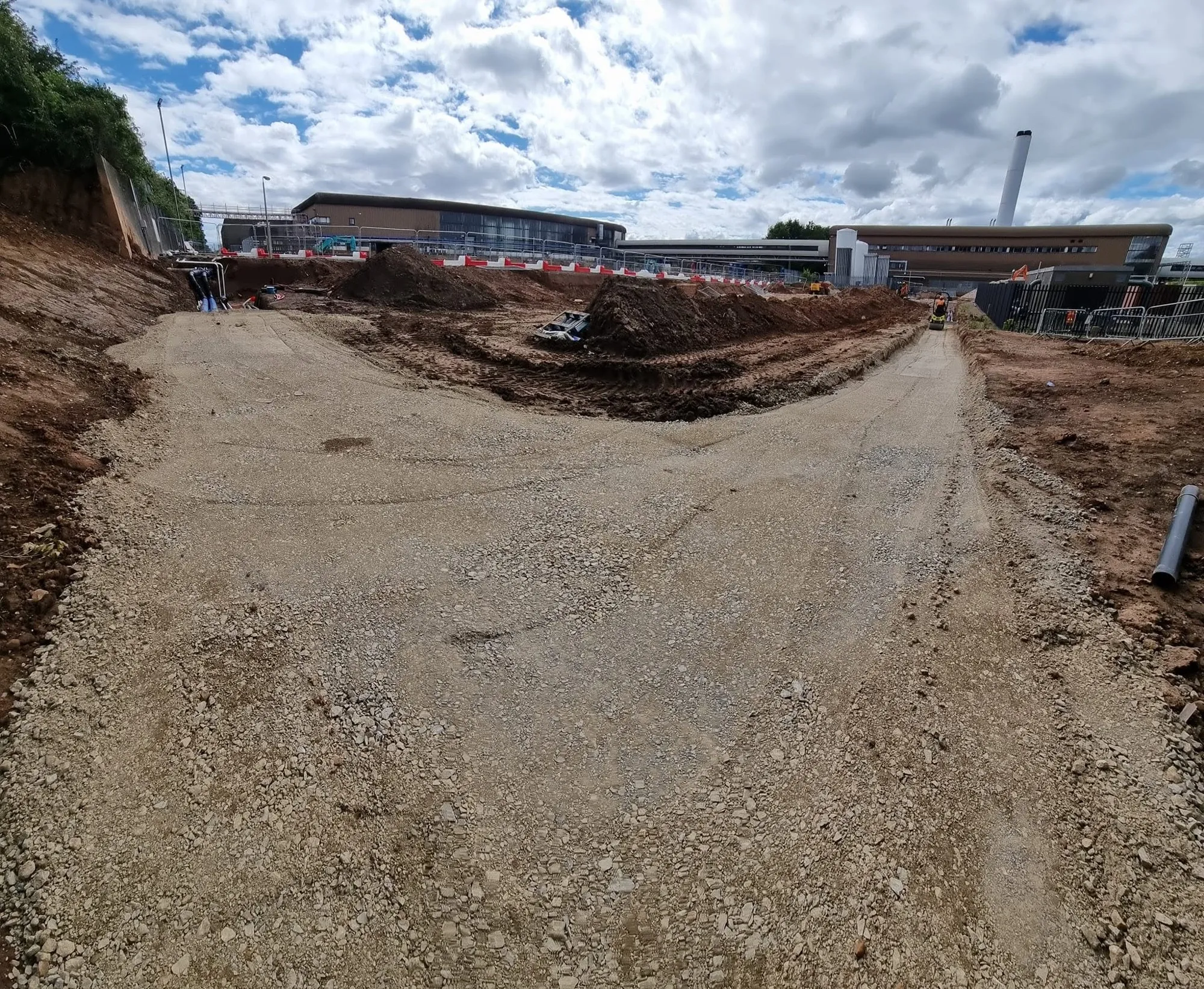 Backfilled and compacted trench route leading towards a commercial building