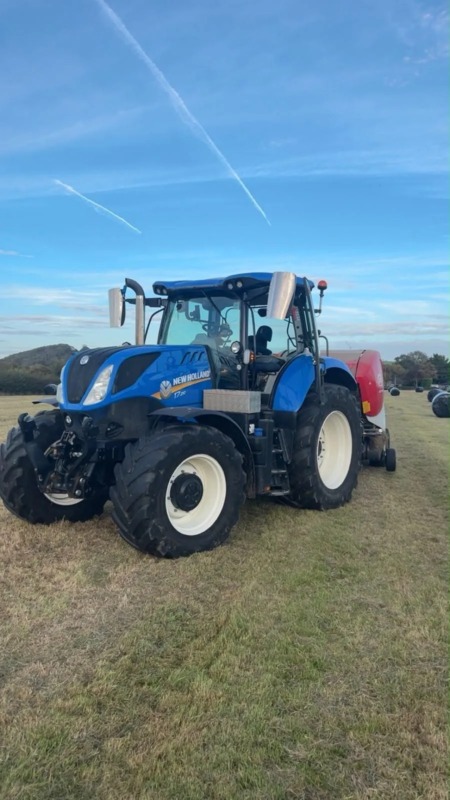 New Holland T7 tractor with a round baler in a field