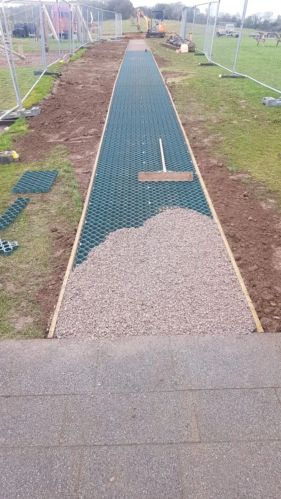 Ground reinforcement grid being filled with gravel on the path