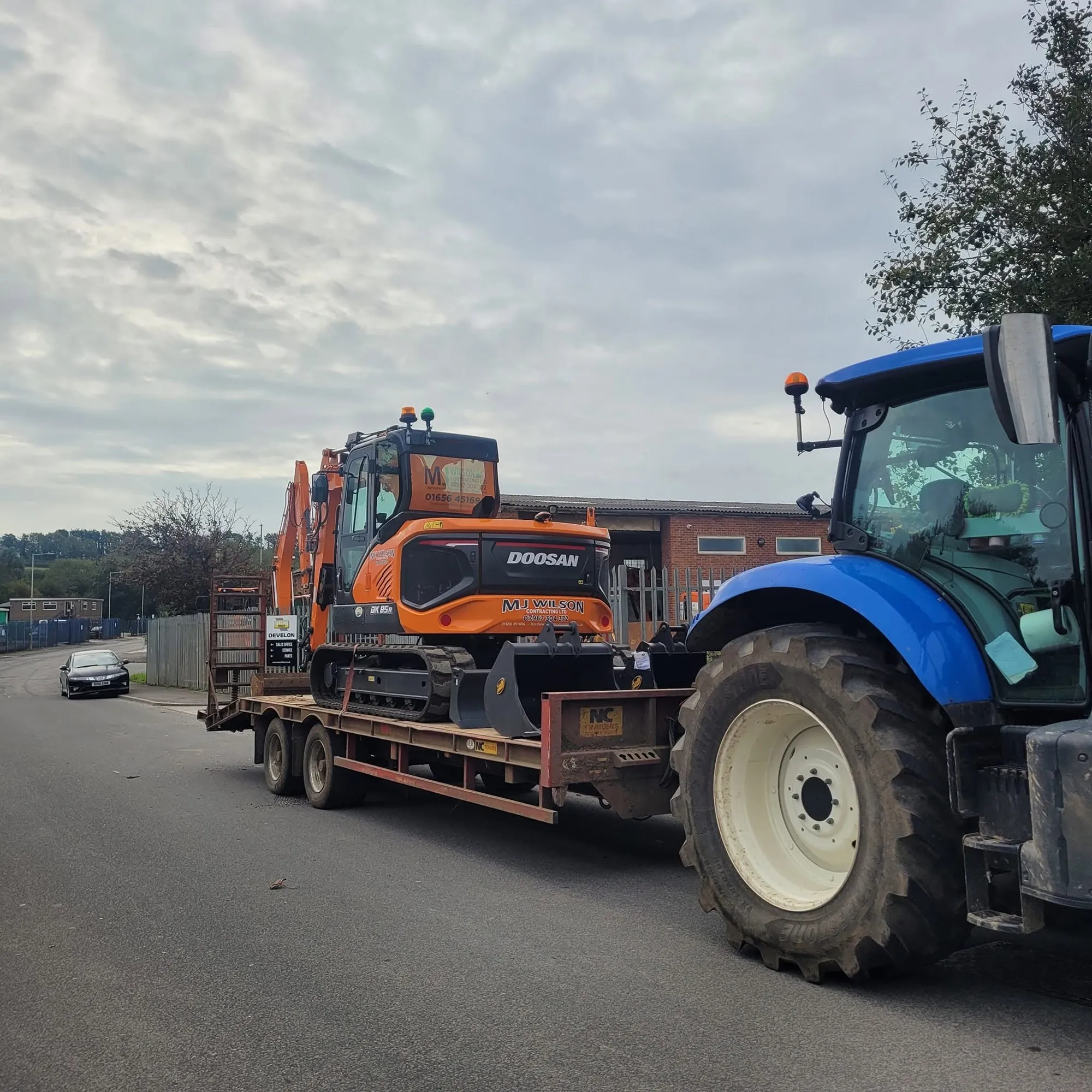 Tractor towing an excavator on a low loader trailer