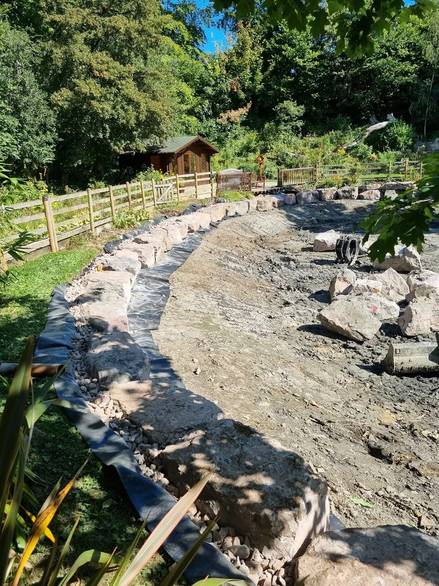 Curved pond bank retained with rows of large block stone