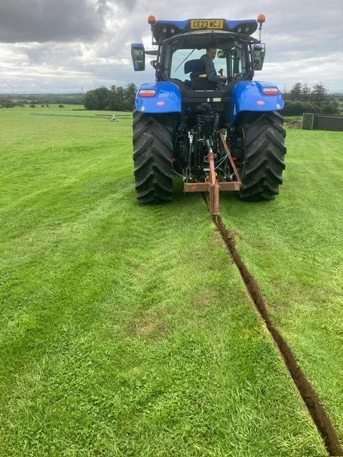 Trencher working across a grass field