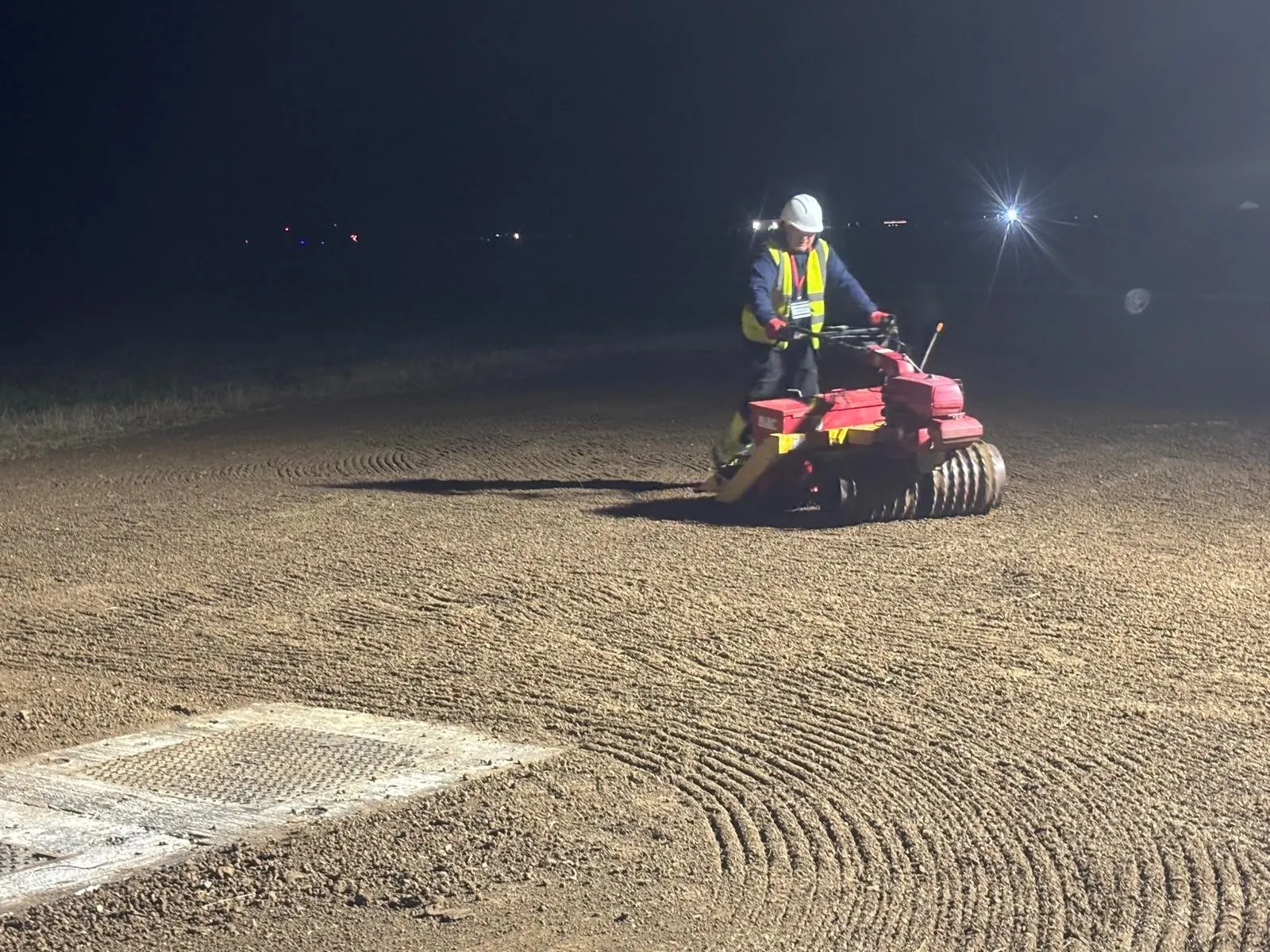 Operative rolling cultivated ground at night under site lighting