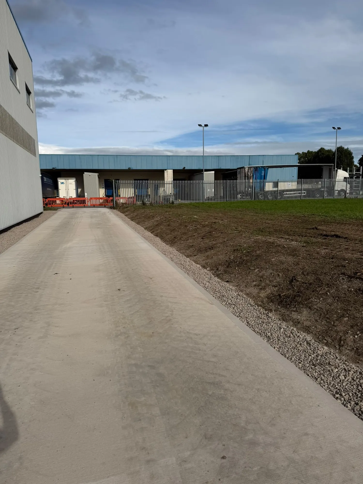 New concrete access road and stoned verge beside an industrial unit