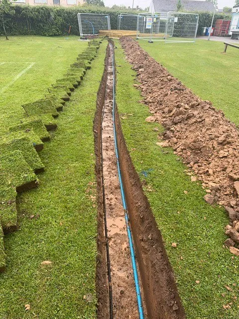 Narrow service trench backfilled across turf