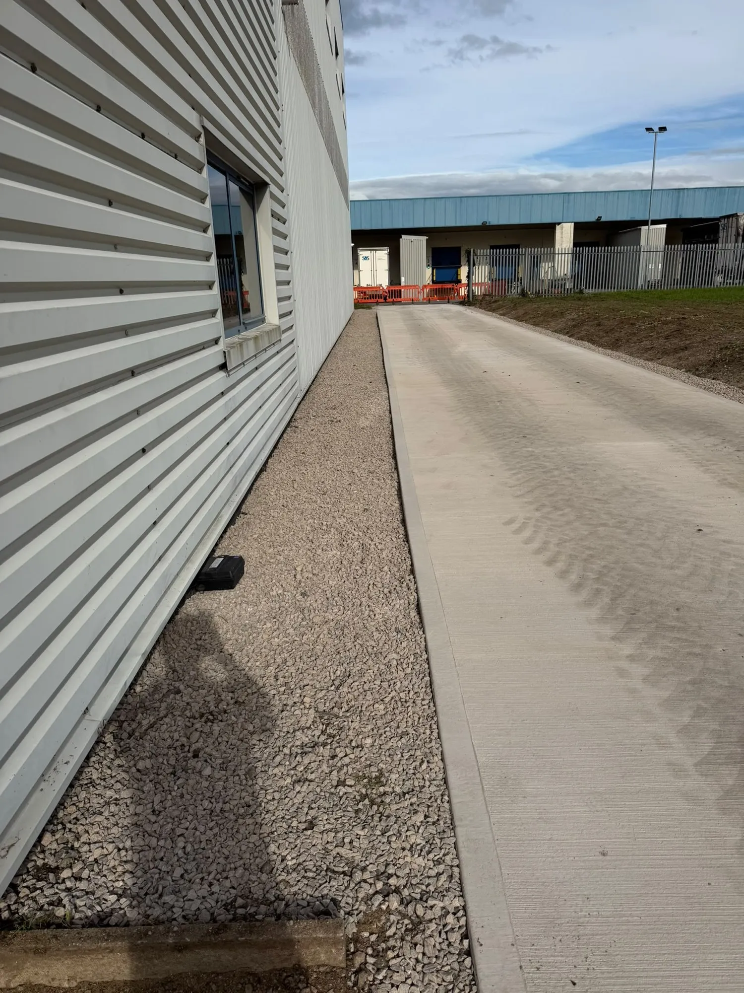 Concrete roadway and gravel margin along the side of an industrial building