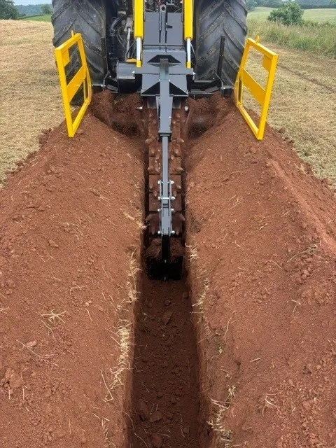 Narrow trench cut by the chain trencher through red soil
